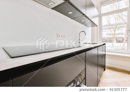 Fragment of interior of black home kitchen with minimalist style white furniture with sink and stove Fragment of interior of black home kitchen with minimalist style white furniture with sink and stove 91305777