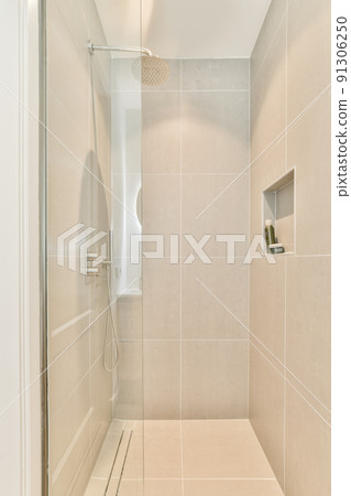 Shower faucets attached to tiled wall near glass partition and ornamental curtail in washroom at home 91306250