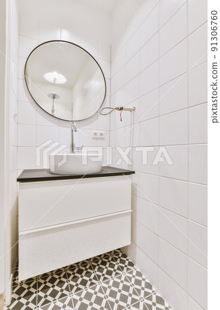 Sink with tap and liquid soap hanging on tiled wall under mirror in contemporary restroom at home 91306760