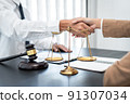 Businesswoman shaking hands with Professional male lawyer after discussing a good deal of contract in the courtroom, Concepts of law, Judge gavel with scales of justice 91307034