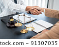 Businesswoman shaking hands with Professional male lawyer after discussing a good deal of contract in the courtroom, Concepts of law, Judge gavel with scales of justice 91307035