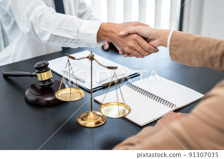 Businesswoman shaking hands with Professional male lawyer after discussing a good deal of contract in the courtroom, Concepts of law, Judge gavel with scales of justice 91307035