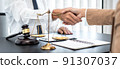 Businesswoman shaking hands with Professional male lawyer after discussing a good deal of contract in the courtroom, Concepts of law, Judge gavel with scales of justice 91307037