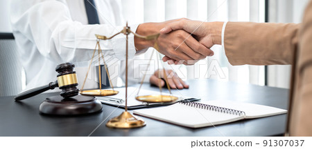 Businesswoman shaking hands with Professional male lawyer after discussing a good deal of contract in the courtroom, Concepts of law, Judge gavel with scales of justice 91307037