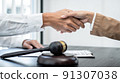 Businesswoman shaking hands with Professional male lawyer after discussing a good deal of contract in the courtroom, Concepts of law, Judge gavel with scales of justice 91307038
