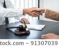 Businesswoman shaking hands with Professional male lawyer after discussing a good deal of contract in the courtroom, Concepts of law, Judge gavel with scales of justice 91307039