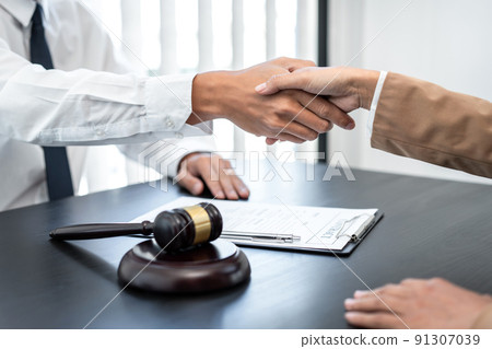 Businesswoman shaking hands with Professional male lawyer after discussing a good deal of contract in the courtroom, Concepts of law, Judge gavel with scales of justice 91307039