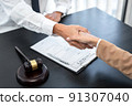 Businesswoman shaking hands with Professional male lawyer after discussing a good deal of contract in the courtroom, Concepts of law, Judge gavel with scales of justice 91307040