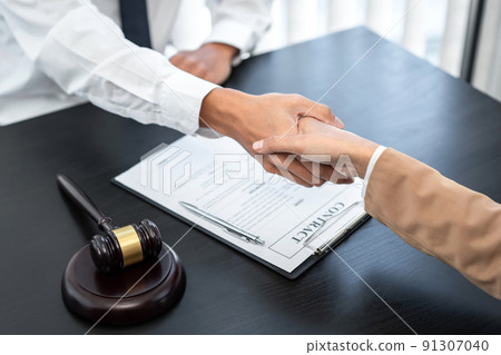 Businesswoman shaking hands with Professional male lawyer after discussing a good deal of contract in the courtroom, Concepts of law, Judge gavel with scales of justice 91307040