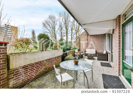Stylish brick balcony with glass table and chairs Stylish brick balcony with glass table and chairs 91307228