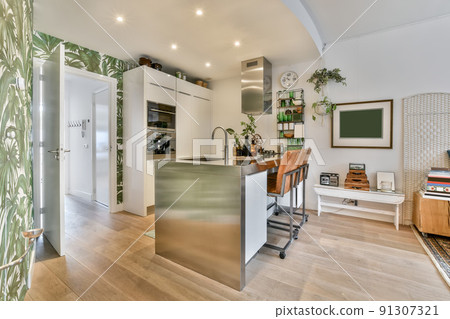 Corner well-equipped kitchen with a breakfast bar in a bright open studio apartment 91307321