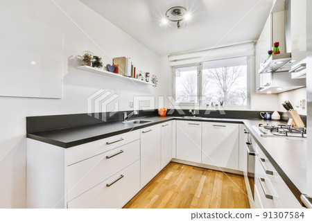 Stylish kitchen with a black countertop and a white kitchen set 91307584