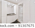 Tiled shower cabin with glass door located near sink and mirror in light restroom in contemporary apartment 91307675