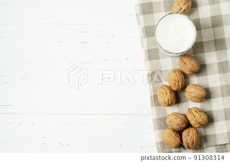 Milk from walnuts and nuts on a white wooden background. Products containing vegetable protein, vitamins, and useful amino acids. For a healthy and vegetarian diet. Copy space. 91308314
