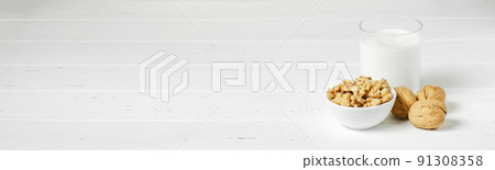 Milk from walnuts and nuts on a white wooden background. Products containing vegetable protein, vitamins, and useful amino acids. For a healthy and vegetarian diet. Copy space. 91308358