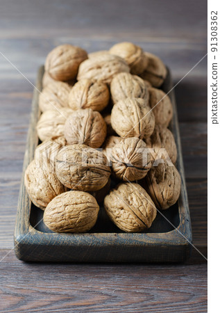Walnuts on a dark brown wooden background. Close up. Selective focus, side view. 91308362