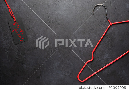 Red coat hangers on a dark concrete background. Black Friday - handwritten inscription on the tag. The concept of holiday sales. Copy space Red coat hangers on a dark concrete background. Black Friday - handwritten inscription on the tag. The concept of holiday sales. Copy space 91309008