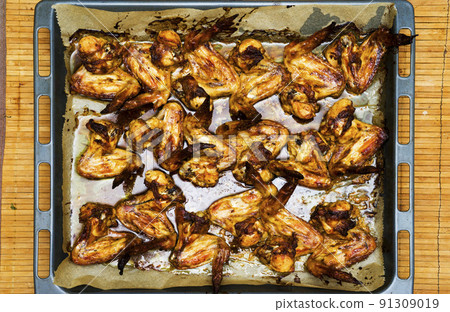 Close up barbecue grilled chicken wings in a cast-iron frying pan with assorted sauces on a stone background. Top view. Flat lay. Crispy tasty snack for beer. Closeup Close up barbecue grilled chicken wings in a cast-iron frying pan with assorted sauces on a stone background. Top view. Flat lay. Crispy tasty snack for beer. Closeup 91309019