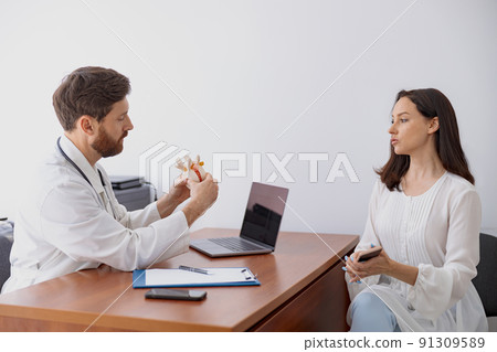 Male doctor consults patient and shows the model of several spines in modern clinic Male doctor consults patient and shows the model of several spines in modern clinic 91309589