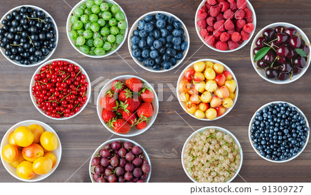 A set of berries in the round plates. Brown wooden background A set of berries in the round plates. Brown wooden background 91309727
