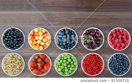 A set of berries in the round plates. Brown wooden background. Copy space. 91309728
