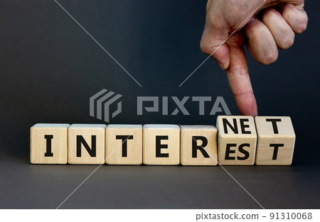 Internet and interest symbol. Businessman turns wooden cubes and changes the words interest to internet. Beautiful grey background. Copy space. Business, internet and interest concept. Internet and interest symbol. Businessman turns wooden cubes and changes the words interest to internet. Beautiful grey background. Copy space. Business, internet and interest concept. 91310068