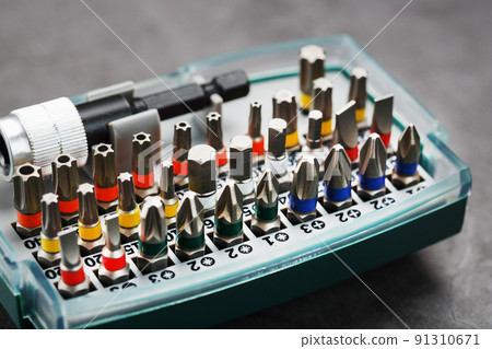 A set of different bits for screwdrivers and repairs in a box on a gray background 91310671