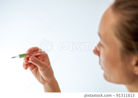Woman being sick having flu looking at temperature on thermometer. Woman being sick having flu looking at temperature on thermometer. 91311813