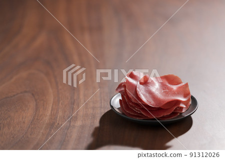 saucer with this slices of bresaola on walnut wood table saucer with this slices of bresaola on walnut wood table 91312026