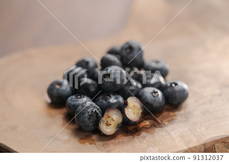 Fresh blueberries on wood board one berry is cut in halves Fresh blueberries on wood board one berry is cut in halves 91312037
