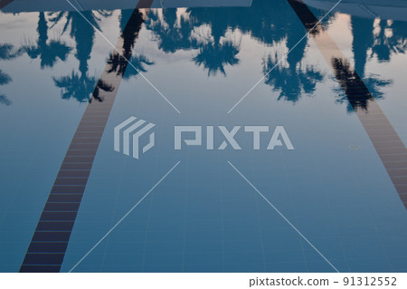 Reflection of palm trees in the pool at sunset. Reflection of palm trees in the pool at sunset. 91312552