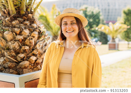 Closeup portrait of positive young beautiful woman looking at camera. Redhead girl walking in the park in a warm sunny day. Urban lifestyle concept. Traveler 91313203