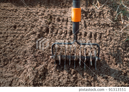 Close up of an new metal garden rake cleaning earth at spring time. Seasonal work Close up of an new metal garden rake cleaning earth at spring time. Seasonal work 91313551