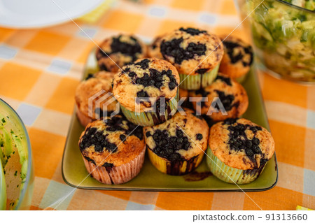 Homemade sweet delicious chip muffins with berry berries in plate on light color background. Picnic at a local park. Homemade sweet delicious chip muffins with berry berries in plate on light color background. Picnic at a local park. 91313660