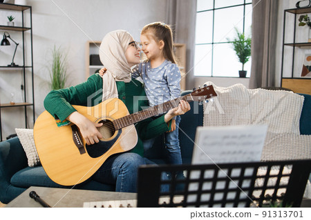 Muslim mom and little happy girl in music therapy by playing guitar on music room. Muslim mom and little happy girl in music therapy by playing guitar on music room. 91313701
