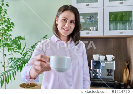 Young woman offering cup of coffee, home kitchen interior coffee machine background 91314730