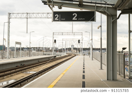 Walk way in train station with no people. Empty Passanger train railway station platform. Sign board with number of platform Walk way in train station with no people. Empty Passanger train railway station platform. Sign board with number of platform 91315785