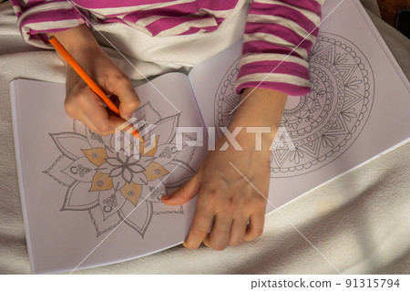 Female painting mandalas antistress page to combat stress. Relaxing hobby mental wellbeing and art therapy. Woman paints sketch, meditative process of coloring pages. Self expression by art Female painting mandalas antistress page to combat stress. Relaxing hobby mental wellbeing and art therapy. Woman paints sketch, meditative process of coloring pages. Self expression by art 91315794