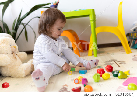 happy funny kid curly baby girl with educational toy blocks flowers. Children play at day care or preschool. Mess in kids room. Toddler build tower in kindergarten. Child playing with colorful toys 91316594