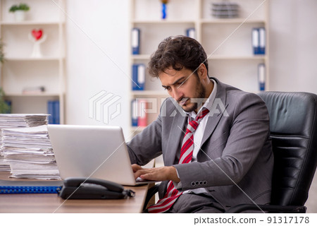 Young male employee unhappy with excessive work in the office 91317178