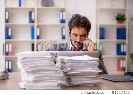 Young male employee unhappy with excessive work in the office 91317191