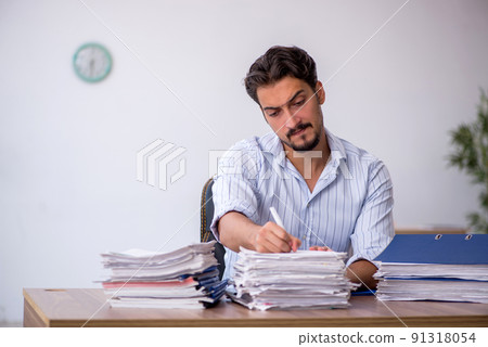 Young male employee and too much work in the office Young male employee and too much work in the office 91318054