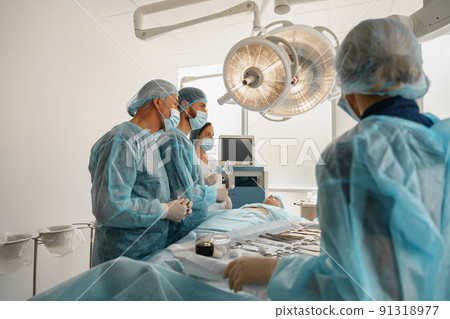 Concentrated surgical team working with a patient in an operation room Concentrated surgical team working with a patient in an operation room 91318977