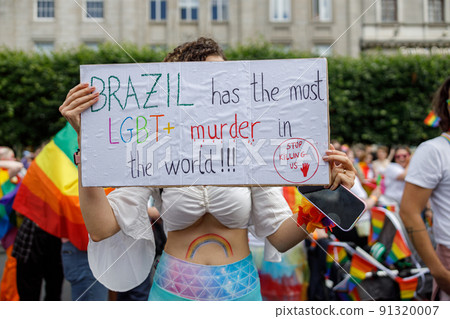 Diverse people are walking on a gay pride parade on the city streets with flags 91320007