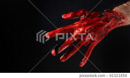 Close-up of a male hand stained with blood on a black background. Close-up of a male hand stained with blood on a black background. 91321850