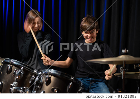 Young woman teaching boy to play drums. Young woman teaching boy to play drums. 91321892