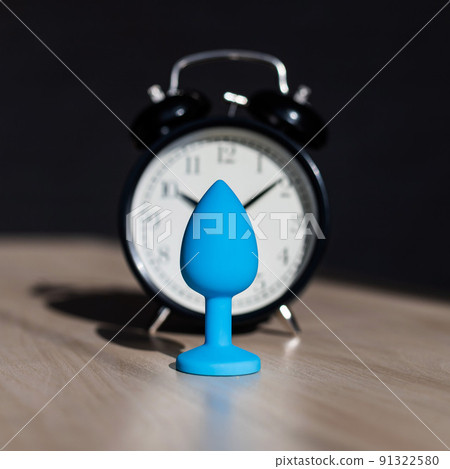 Blue latex anal plug and alarm clock on a... - Stock Photo [91322580]