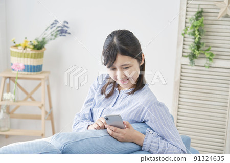 A woman using a smartphone in the living room A woman using a smartphone in the living room 91324635