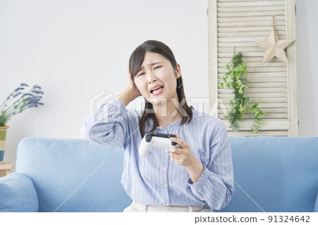A woman holding her head playing a video game alone in the living room A woman holding her head playing a video game alone in the living room 91324642
