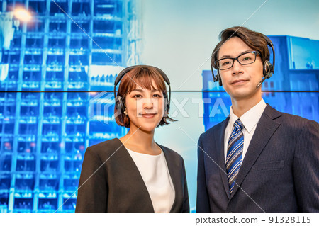 Businesswoman and businessman in headset talking in front of a huge display Businesswoman and businessman in headset talking in front of a huge display 91328115